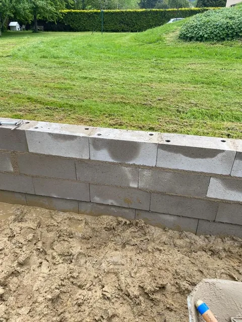 Muret de soubassement en parpaings en limite de jardin.
